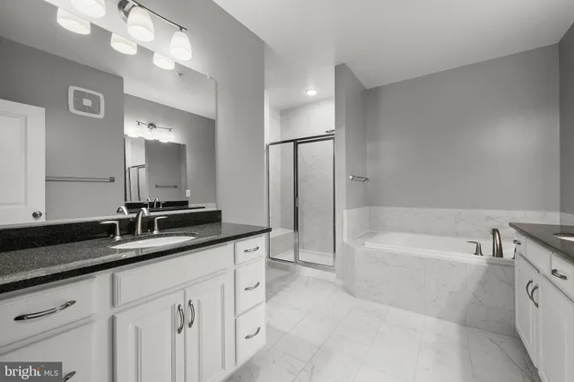 a spacious bathroom with a granite countertop sink mirror and a bathtub