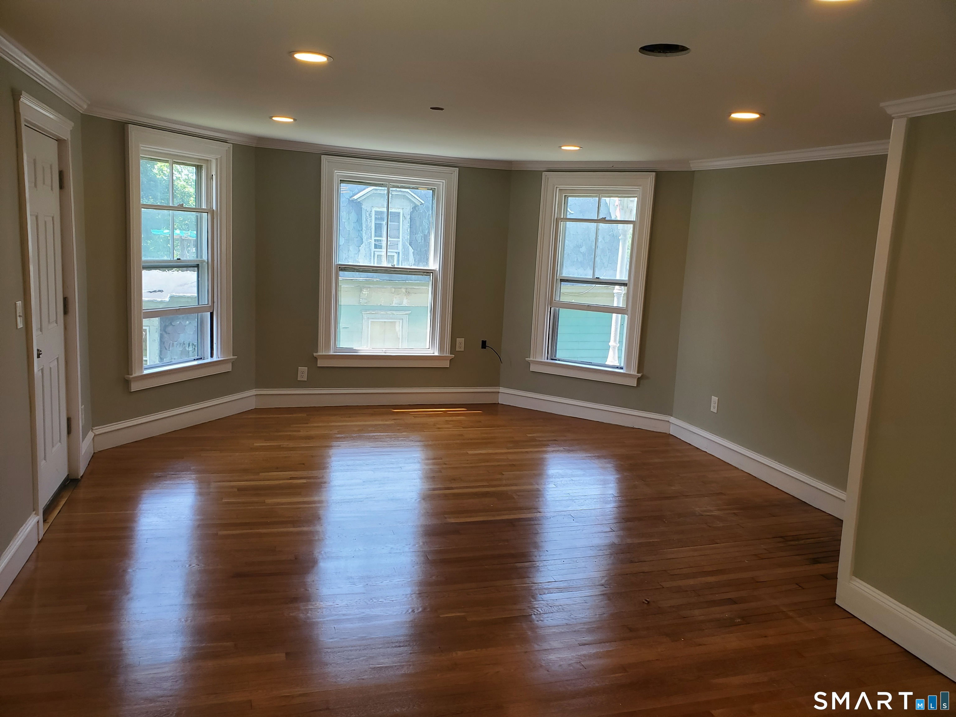 31 Bellevue Street Windham, CT 06226 - Photo 6 of 16 an empty room with wooden floor and windows with curtains view
