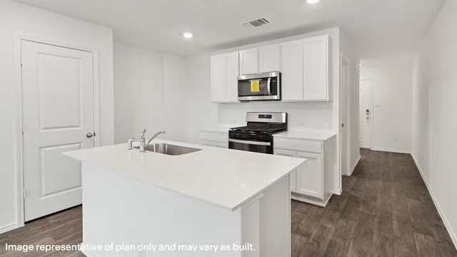 a kitchen with a sink a stove and white cabinets