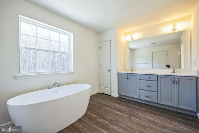 a spacious bathroom with double vanity sink a mirror a bathtub and window