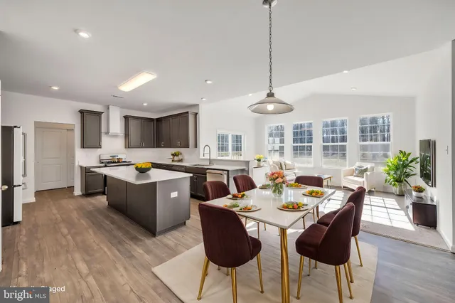 a kitchen with stainless steel appliances kitchen island granite countertop a dining table chairs and white cabinets