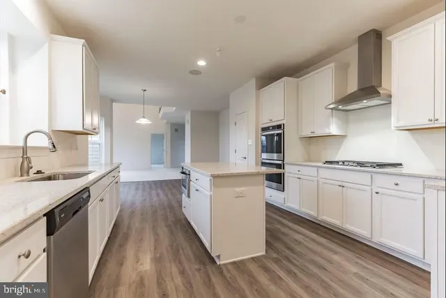 a large kitchen with stainless steel appliances granite countertop a lot of counter space and wooden floors