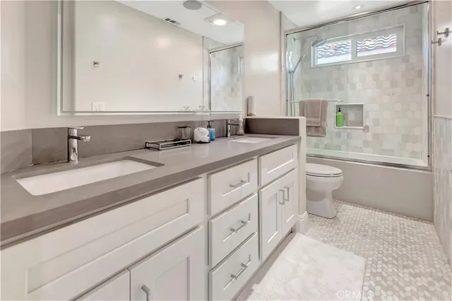 a bathroom with a double vanity sink toilet and a mirror