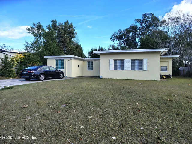 a view of a house with backyard and trees