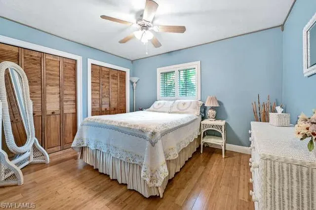 a bedroom with a bed next to a large window with wooden floor