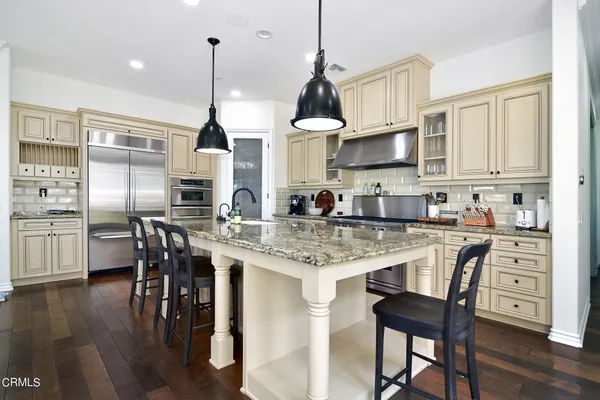 a kitchen with stainless steel appliances granite countertop a stove top oven a sink a dining table and chairs with wooden floor