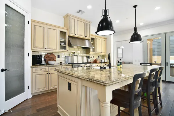 a kitchen with stainless steel appliances granite countertop a sink a stove a refrigerator and white cabinets with wooden floor