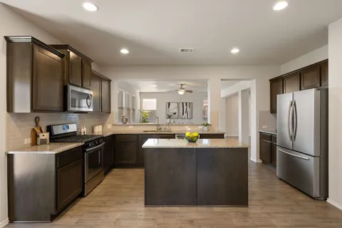 a kitchen with stainless steel appliances granite countertop a refrigerator a oven a sink dishwasher and wooden cabinets
