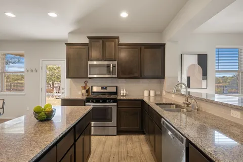 a kitchen with stainless steel appliances granite countertop sink stove microwave and cabinets