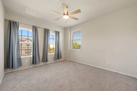 an empty room with windows and ceiling fan