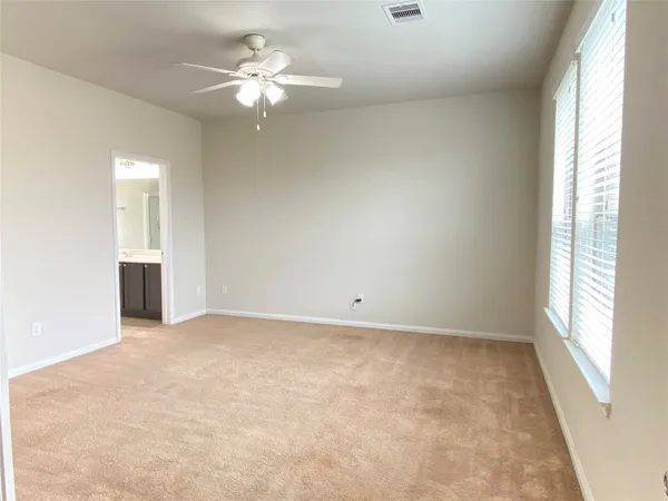 an empty room with windows and ceiling fan