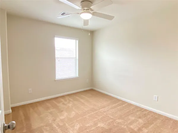 an empty room with a window and a fan