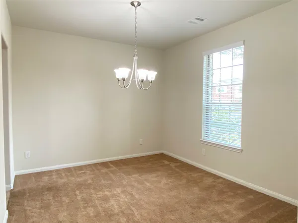an empty room with a chandelier fan and windows