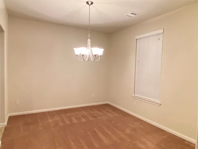 an empty room with a chandelier fan and wooden floor