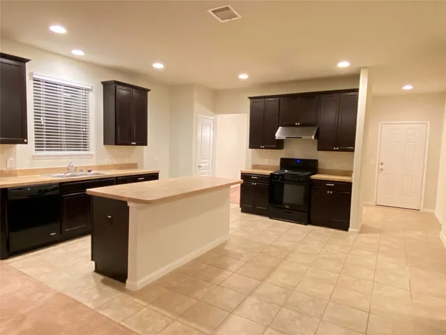 a large kitchen with kitchen island granite countertop a sink and a stove top oven