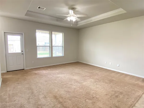 an empty room with windows and chandelier fan