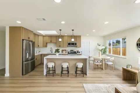 a kitchen with stainless steel appliances a dining table chairs refrigerator and cabinets