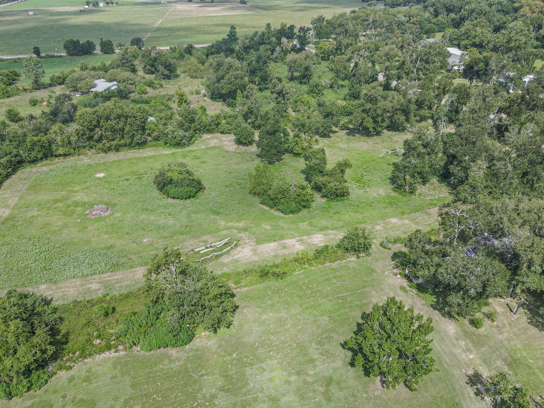 0 Buckskin Road Wallis, TX 77485 - Photo 2 of 6 This aerial view showcases a spacious, green lot surrounded by mature trees with open grassy areas, ideal for building a home or enjoying outdoor activities. The landscape offers privacy and a serene, rural setting.