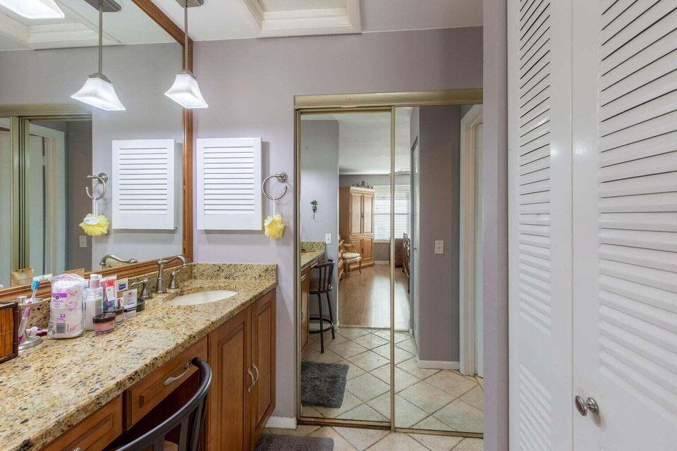 13045 Albright Court, Unit 12 Wellington, FL 33414 - Photo 7 of 11 a bathroom with a granite countertop sink and a mirror