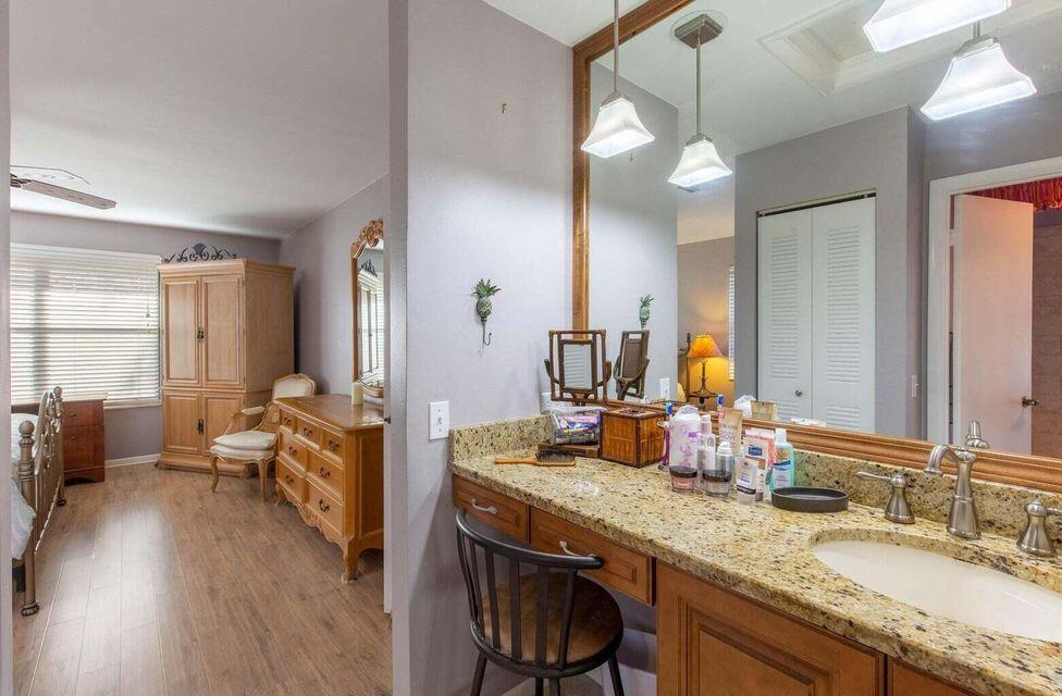 13045 Albright Court, Unit 12 Wellington, FL 33414 - Photo 10 of 11 a en suite bathroom with a granite countertop sink mirror and wooden floor