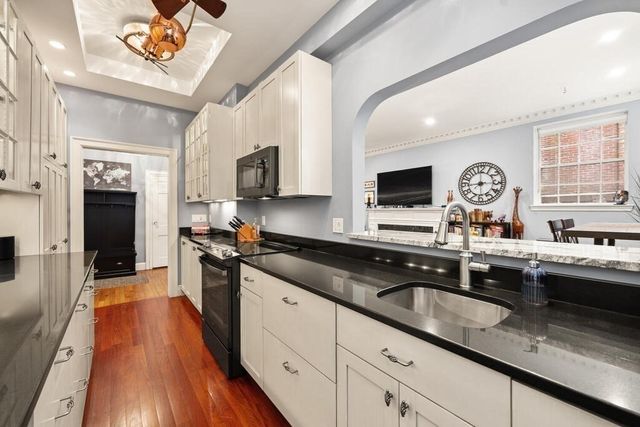 a kitchen with granite countertop a sink dishwasher stove and oven with wooden floor