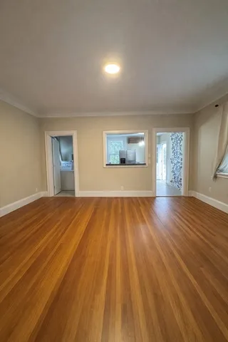 a view of empty room with window and wooden floor