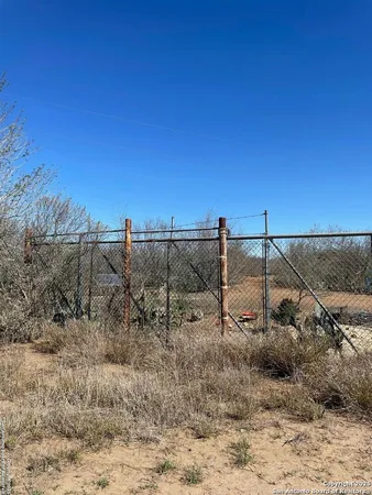 a view of a dry yard with trees in the background