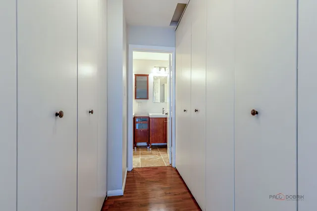 a view of a hallway with wooden floor and closet with bathroom