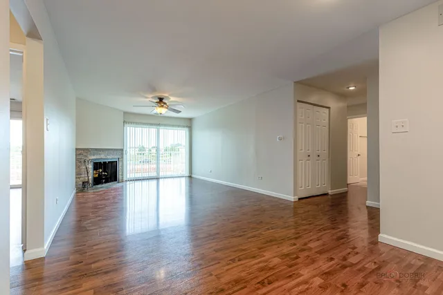 an empty room with wooden floor fireplace and windows