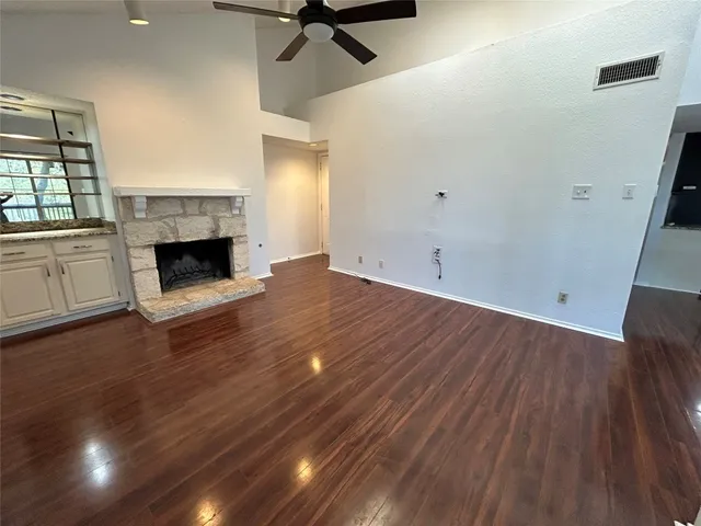 an empty room with wooden floor fireplace and windows
