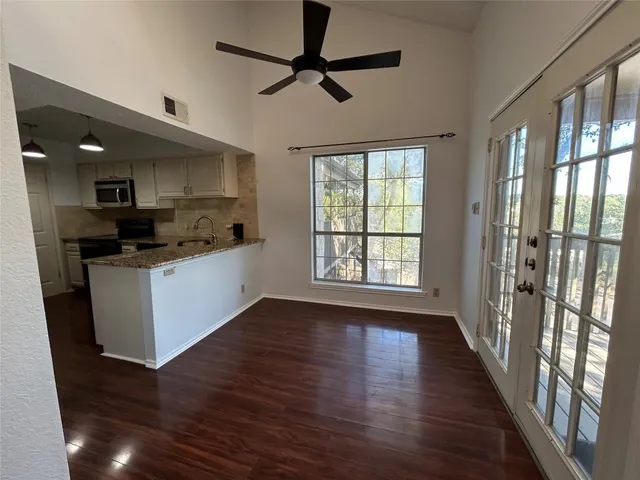 a kitchen with stainless steel appliances a stove top oven a sink a refrigerator with a dining table and wooden floor