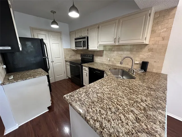 a kitchen with kitchen island granite countertop a sink stainless steel appliances and cabinets