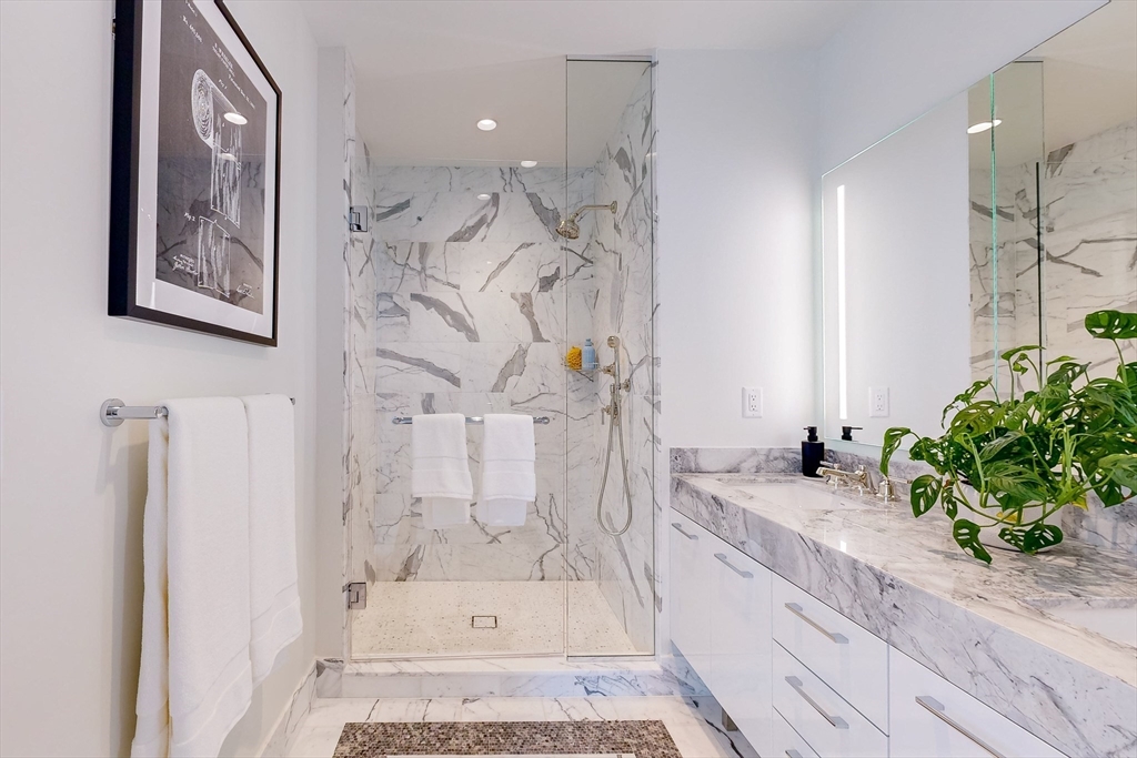 240 Devonshire Street, Unit 4706 Boston, MA 02110 - Photo 9 of 40 a bathroom with a granite countertop sink a mirror a bathtub and shower