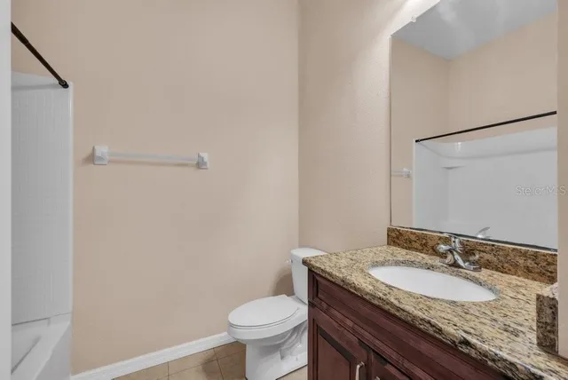 an empty room with a chandelier fan and windows