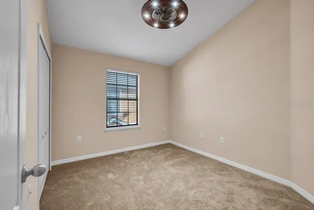 an empty room with ceiling fan and windows