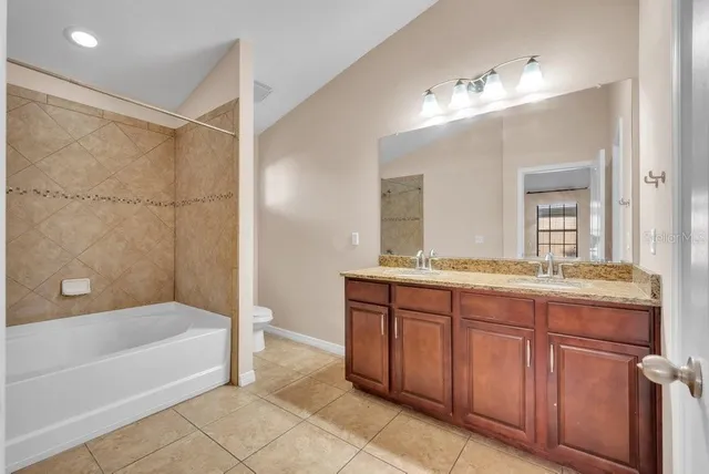 a bathroom with a granite countertop bathtub a sink and a large mirror