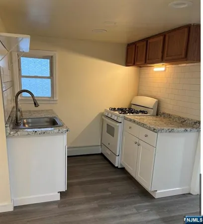 a kitchen with granite countertop a sink a stove and cabinets