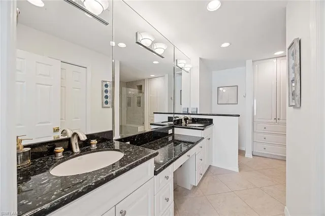 a bathroom with a granite countertop double vanity sink a mirror and a shower