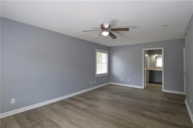 a view of empty room with wooden floor and ceiling fan