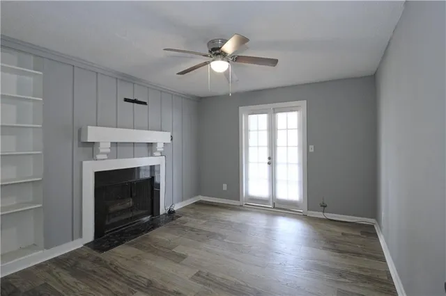 a view of an empty room with wooden floor fireplace and a window