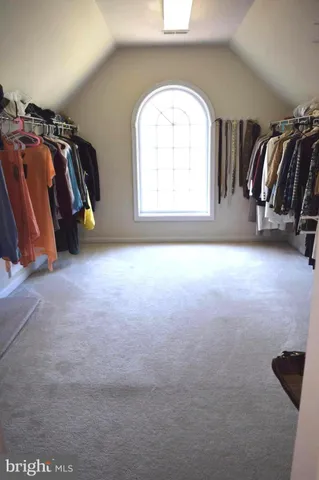 a view of walk in closet with clothes and shoes