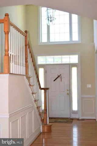 a view of front door with hallway and wooden floor