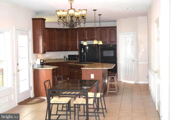 a kitchen with kitchen island granite countertop a dining table chairs and a refrigerator