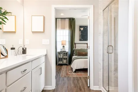 a en suite bathroom with a granite countertop double vanity sink a mirror and a shower