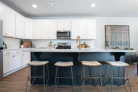 a kitchen with stainless steel appliances granite countertop a table chairs microwave and sink