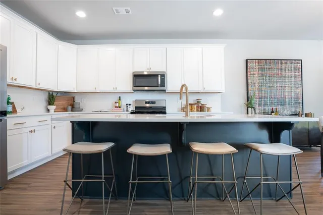 a kitchen with stainless steel appliances granite countertop a table chairs microwave and sink