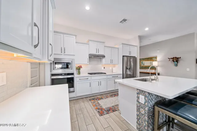 a kitchen with a sink a stove a refrigerator and white cabinets