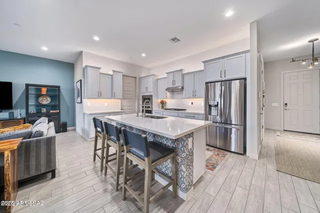 a kitchen with stainless steel appliances a dining table chairs refrigerator and microwave