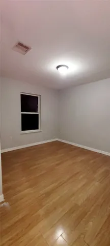 a view of an empty room with wooden floor and windows