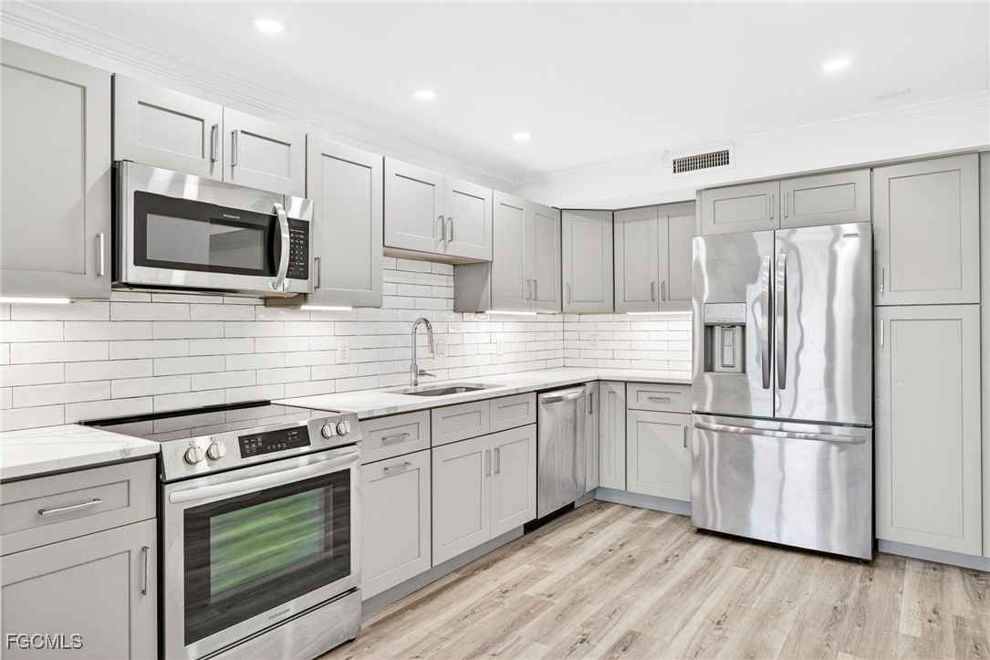 200 Periwinkle Way, Unit 124 Sanibel, FL 33957 - Photo 13 of 50 a kitchen with cabinets stainless steel appliances and wooden floor
